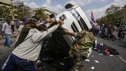 Des manifestants renversent un fourgon des forces de l'ordre &agrave; Bangkok, en Tha&iuml;lande, le 17 f&eacute;vrier 2014. (ATHIT PERAWONGMETHA / REUTERS)