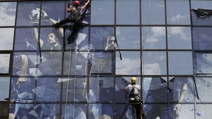 Les effigies des joueurs de l'&eacute;quipe de France de football sont retir&eacute;es de la fa&ccedil;ade du si&egrave;ge de la F&eacute;d&eacute;ration fran&ccedil;aise de football, apr&egrave;s l'&eacute;chec de l'Euro 2012, le 28 juin 2012.&nbsp; (KENZO TRIBOUILLARD / AFP)