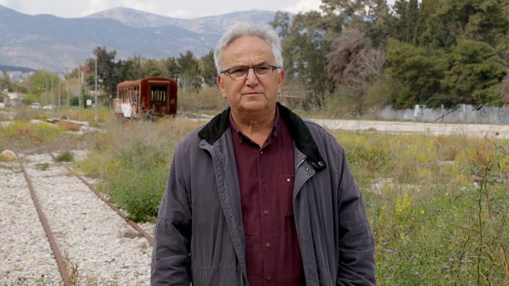 Sotiris Raftopoulos, président de l'association panhellénique des retraités du train, près d'une gare et de voies abandonnées en banlieue nord d'Athènes (Grèce), le 11 avril 2023. (VALENTINE PASQUESOONE / FRANCEINFO)