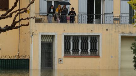 Des habitants du Muy (Var) sortent sur leur balcon et regardent les rues inondées de leur commune, le 24 novembre 2019. (VALERY HACHE / AFP)