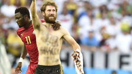 Un streaker n&eacute;onazi est raccompagn&eacute; par le milieu de terrain ghan&eacute;en&nbsp;Sulley Muntari apr&egrave;s avoir interrompu le match opposant l'Allemagne au Ghana en Coupe du monde de football &agrave; Fortaleza (Br&eacute;sil), le 21 juin 2014. (YANG LEI / CHINE NOUVELLE / SIPA)