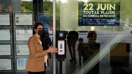 Natacha Bouchaudon, directrice de l'UGC Paris 19, se nettoye les mains avec un distributeur de gel hydroalcoolique disposé dans le cinéma.&nbsp; (THOMAS COEX / AFP)