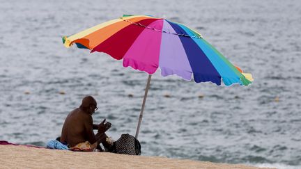 Un vacancier sous un parasol sur une plage. Photo d'illustration. (VINCENT ISORE / MAXPPP)