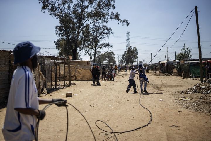 Démontage d'un réseau électrique sauvage dans un quartier de Johannesburg par des employés d'Eskom, le 29 septembre 2020. (MICHELE SPATARI / AFP)