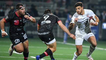 Le Toulousain Romain Ntamack, ballon en main, chassé par les Lyonnais pour la 7e journée de Top 14, dimanche 17 octobre, au stade de Gerland. (PHILIPPE DESMAZES / AFP)