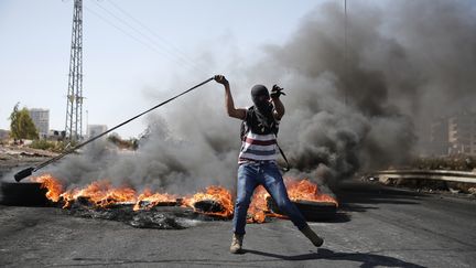 Un Palestinien affronte &agrave; coup de jets de pierre des soldats isra&eacute;liens le 11 octobre 2015 pr&egrave;s de&nbsp;Ramallah en Cisjordanie. (ABBAS MOMANI / AFP)