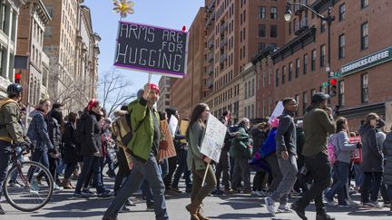 Un&nbsp;manifestant brandit une pancarte jouant sur le double sens du mot "arms", qui&nbsp;désigne&nbsp;les bras comme les armes à feu, samedi 24 mars 2018 à Washington. On peut y lire "Les bras, c'est fait pour les câlins". (ALEX EDELMAN / AFP)