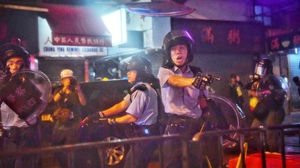Des policiers sortent leurs armes lors d'une manifestation, à Hong Kong (Chine), le 25 août 2019. (LILLIAN SUWANRUMPHA / AFP)