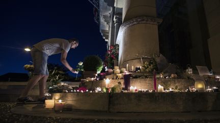 Un homme dépose une rose au pied de la mairie de&nbsp;Saint-Etienne-du-Rouvray, le 26 juillet 2016.&nbsp;Les hommages se sont poursuivis pendant la nuit. (MAXPPP)