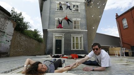 Des visiteurs posent sur l'oeuvre toute en illusion d'optique de l'artiste argentin Leonardo Erlich install&eacute;e &agrave; Londres (Royaume-Uni), le 25 juin 2013. (LUKE MACGREGOR / REUTERS)