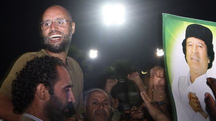 Seif al-Islam Kadhafi, fils de l'ancien «Guide» libyen Mouammar, entouré de ses partisans et de journalistes au complexe résidentiel de son père, le 23 août 2011, à Tripoli. (IMED LAMLOUM / AFP POOL / AFP)