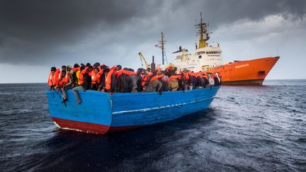 Des réfugiés entassés sur un bateau en bois, non loin de l'"Aquarius", navire de sauvetage des ONG SOS Méditerranée et Médecins sans frontières, le 11 décembre 2016, en mer Méditerranée. (LAURIN SCHMID/ SOS MEDITERRANEE / PICTURE ALLIANCE / AFP)