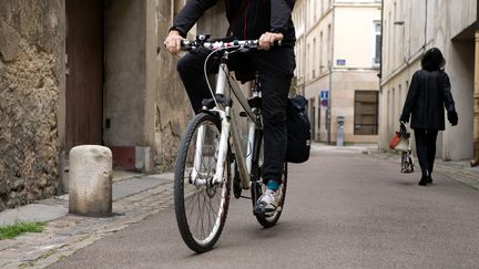 Un homme à vélo croise une piétonne dans une petite rue à Chalon-sur-Saône (Saône-et-Loire). (EDOUARD ROUSSEL / MAXPPP)