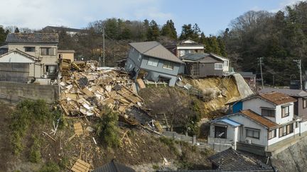 Des maisons endommagées à Wajima, dont une complètement rasée par le tremblement de terre. (FRED MERY / AFP)