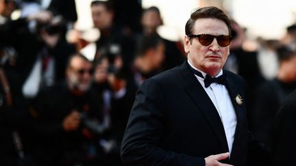 Benoît Magimel a monté les marches de Cannes pour la deuxième fois en 2023, mais toujours sans quitter ses lunettes fumées. Après "Omar la fraise" vendredi 20 mai, place à "La passion de Dodin Bouffant", où l'acteur incarne un gastronome. (CHRISTOPHE SIMON / AFP)