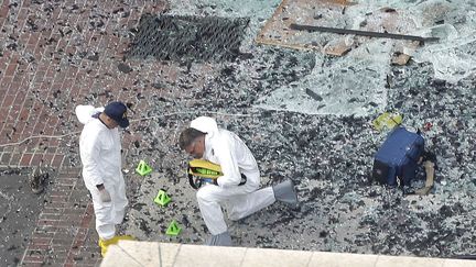 Deux enqu&ecirc;teurs ramassent des d&eacute;bris sur les lieux des explosions &agrave; Boston (Etats-Unis), le 16 avril 2013. (ELISE AMENDOLA / AP / SIPA)