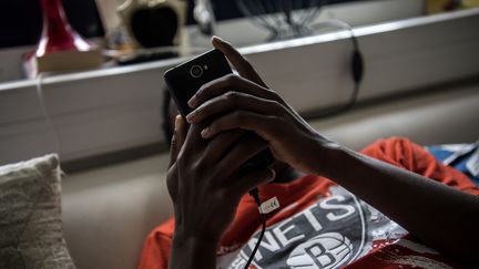 Un jeune migrant utilise son portable dans un centre de Médecins sans frontières à Pantin (Seine-Saint-Denis), le 3 juillet 2018. (CHRISTOPHE ARCHAMBAULT / AFP)