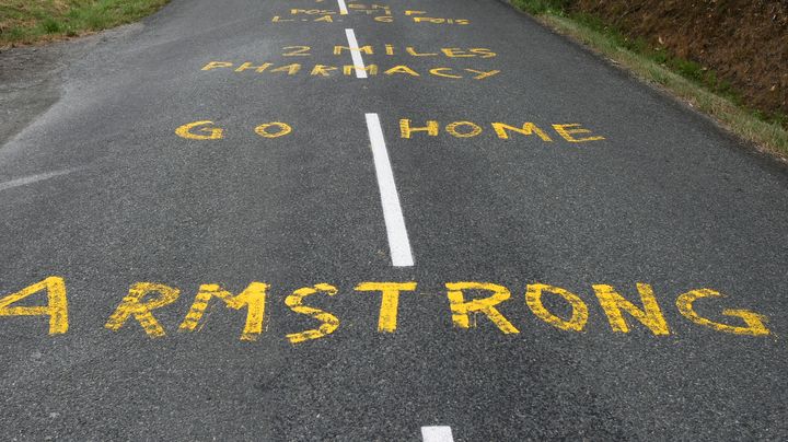 "Rentre chez toi, Armstrong", inscrit sur la route du Tour de France lors d'une &eacute;tape entre Limoges et Issoudun, le 14 juillet 2009. (JOEL SAGET / AFP)