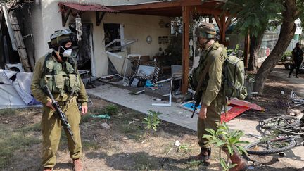 Deux soldats israéliens en patrouille dans le kibboutz de Kfar Aza, où une centaine de personnes ont été tuées par des commandos du Hamas. (JACK GUEZ / AFP)