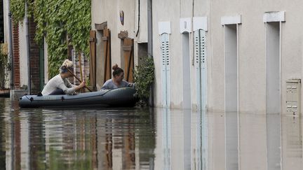 Deux femmes tentent d'entrer dans leur domicile inondé, à Montargis (Loiret), le 1er juin 2016.&nbsp; (GUILLAUME SOUVANT / AFP)