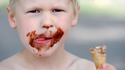 Un garçon de cinq ans appréciant sa glace au chocolat (illustration). (JULIAN STRATENSCHULTE / DPA / AFP)