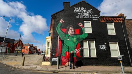 Un fan de Liverpool pose devant la fresque en hommage à l'ancien gardien des Reds Ray Clemence, le 7 octobre 2020 près du stade d'Anfield à Liverpool. (PETER BYRNE / MAXPPP)