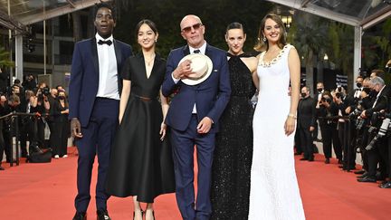 Jacques Audiard, le chapeau sur le coeur, entouré des acteurs et actrices de son film en compétition. De gauche à droite : Makita Samba, Lucie Zhang, Jehnny Beth et Noémie Merlant. Le réalisateur français a traversé pour la première fois le tapis rouge en 1996 avec "Un héros très discret".&nbsp; (JOHN MACDOUGALL / AFP)