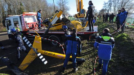 Les gendarmes inspectent la carcasse de l'h&eacute;licopt&egrave;re qui s'est &eacute;cras&eacute; dans la Dordogne, &agrave;&nbsp;Lugon-et-l'Ile-du-Carnay (Gironde), apr&egrave;s l'avoir sorti de l'eau, le 23 d&eacute;cembre 2013.&nbsp; (MEHDI FEDOUACH / AFP)