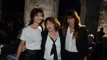 La chanteuse et comédienne Jane Birkin, entourée par deux de ses filles, Charlotte Gainsbourg (à gauche) et Lou Doillon (à droite), au défilé printemps-été Saint Laurent à la Fashion Week de Paris, en 2017. (LAURENT BENHAMOU/SIPA / SIPA)