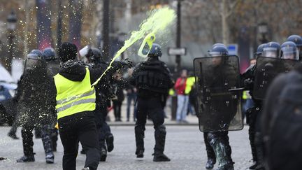 Un manifestant envoie de la peinture jaune sur des policiers. (ALAIN JOCARD / AFP)