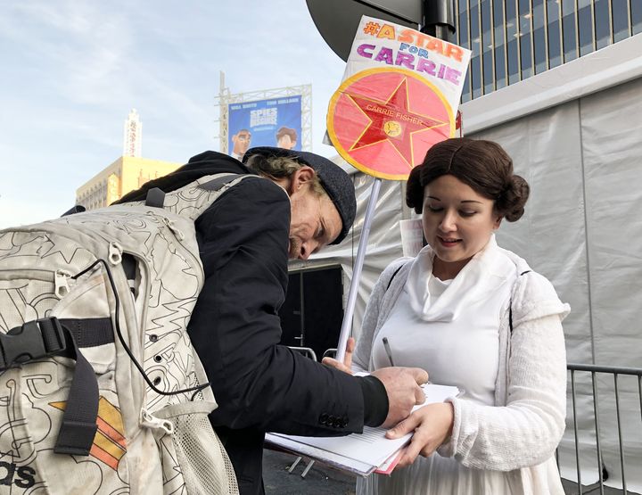 Kristin Grady, en costume de Leia, fait signer sa pétition visant à obtenir une étoile pour Carrie Fischer sur Hollywood Boulevard, à l'occasion de la première mondiale du dernier volet de "Star Wars" le 16 décembre à Los Angeles (JAVIER TOVAR / AFP)