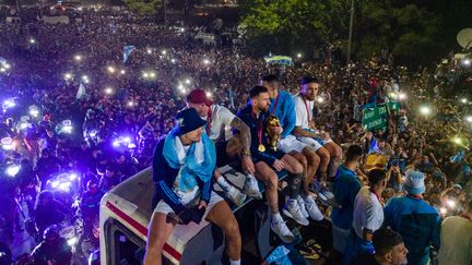 Les joueurs argentins avec Lionel Messi (au centre) célèbrent leur victoire en Coupe du monde à bord d'un bus promotionnel dans la province de Buenos Aires, le 20 décembre 2022. (TOMAS CUESTA / AFP)