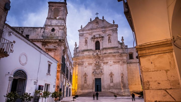 La façade de la basilique Saint Martin du XVIIIe siècle, l'ancien palais ducal et la Tour de l'Horloge, à Martina Franca dans les Pouilles en Italie. (MOMENT RF / GETTY IMAGES)