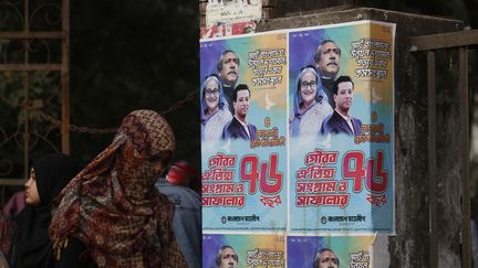 Une femme passe devant des affiches de l'ex-Première ministre bangladaise Sheikh Hasina, de son père et de son fils, Sajeeb Wazed, à Dacca (Bangladesh), le 10 janvier 2024. (RAHMAN ASAD / AFP)