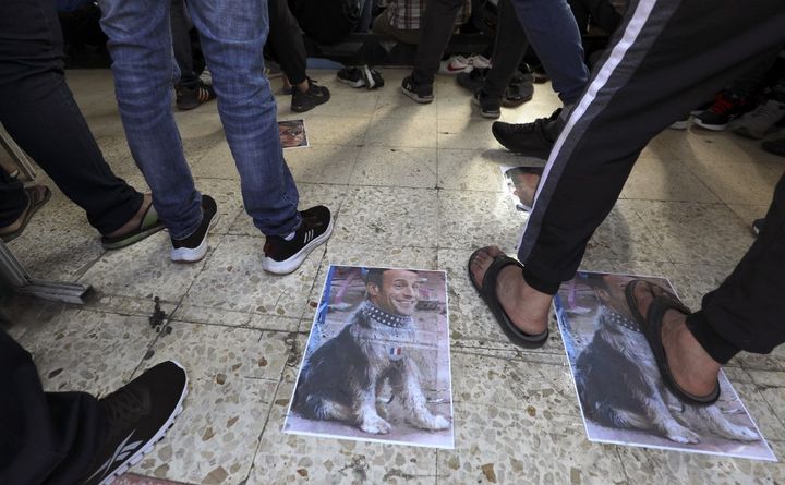 Des photomontages, montrant le visage d'Emmanuel Macron sur le corps d'un chien, piétinés à Ramallah, en Cisjordanie, le 30 octobre 2020. (ABBAS MOMANI / AFP)