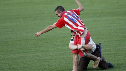 Un agent de s&eacute;curit&eacute; ceinture un supporter qui court dans le stade lors de la pr&eacute;sentation aux journalistes du nouvel attaquant de l'Atletico Madrid, David Villa, Madrid (Espagne), le 15 juillet 2013. (JUAN MEDINA / REUTERS)