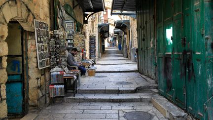 A seller waits for customers in front of a souvenir shop, in the Old City of Jerusalem, in March 2020. (EMMANUEL DUNAND / AFP)