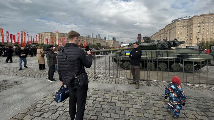 Des visiteurs posent devant un char ukrainien.  (SYLVAIN TRONCHET / RADIO FRANCE)