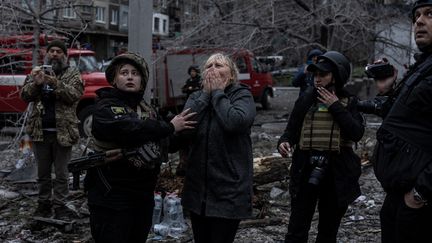 Une femme observe les dégâts d'un immeuble détruit par une frappe russe, le 14 avril 2023, à Sloviansk (Ukraine). (DIEGO HERRERA CARCEDO / ANADOLU AGENCY / AFP)