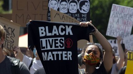 Une manifestante soulève un tee-shirt portant le slogan "Black lives matter" lors d'une manifestation à Washington, le 7 juin 2020. (JOSE LUIS MAGANA / AFP)