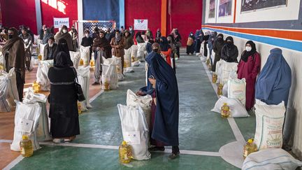 Des Afghanes récupèrent des aides alimentaires mises à disposition par une ONG à Kaboul, en Afghanistan, le 17 juillet 2023. (WAKIL KOHSAR / AFP)