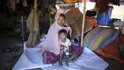 Sabikul Nahar, 21 ans, pose avec un enfant au camp de réfugié de Cox Bazar, Bangladesh, le 9 décembre 2017. (FIRAT YURDAKUL / ANADOLU AGENCY / AFP)