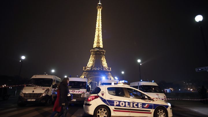 Des passants marchent devant le dispositif policier mis en place autour de la Tour Eiffel, en raison d'un appel anonyme mena&ccedil;ant d'un attentat, le 30 mars 2013 &agrave; Paris. (THOMAS COEX / AFP)