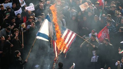 Des manifestants iraniens brûlant&nbsp;des drapeaux américain et israélien, le 6 janvier 2020, à Téhéran.&nbsp; (ATTA KENARE / AFP)