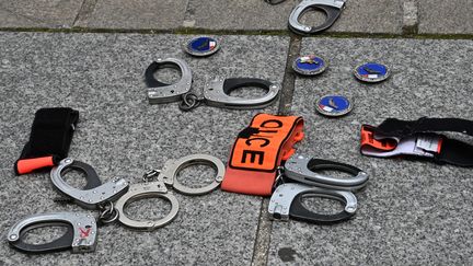 Des menottes et des badges de policiers déposés au sol devant la préfecture de police lors d'une manifestation en réaction aux annonces du ministre de l'Intérieur, Paris, le 17 juin 2020. (BERTRAND GUAY / AFP)