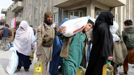 Des Afghans récupèrent des vivres lors d'une distribution d'aide alimentaire à Kaboul, le 7 décembre 2021. (SAYED KHODAIBERDI SADAT / ANADOLU AGENCY / AFP)