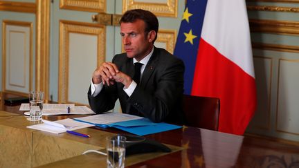 Emmanuel Macron dans son bureau de l'Elysée, écoutant une intervention d'Angela Merkel lors d'une conférence vidéo commune, le 18 mai 2020. (POOL NEW / REUTERS)