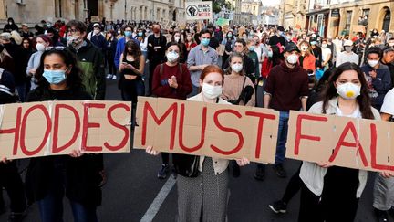 "Rhodes doit tomber", slogan en référence à la statue ornant le fronton de l'Oriel College d'Oxford. Le 9 juin 2020, des centaines de manifestants ont réclamé, dans les rues d'Oxford, le démontage de la statue. (ADRIAN DENNIS / AFP)