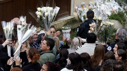 Des habitants déposent des bouquets de fleurs devant l'immeuble de Sedan (Ardennes) où Loana, 10 ans, a été retrouvée morte, le 19 octobre 2023. (FRANCOIS NASCIMBENI / AFP)