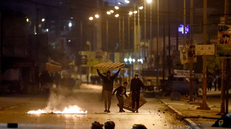 Des manifestants&nbsp;bloquent une rue&nbsp;d'Ettadhamen (Tunisie), le 17 janvier 2021. (FETHI BELAID / AFP)